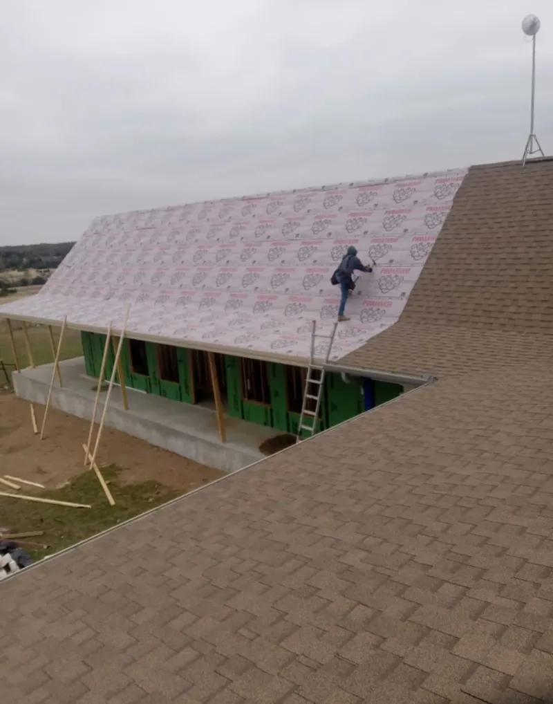 Worker preparing underlayment for a metal roof installation in Stephenville